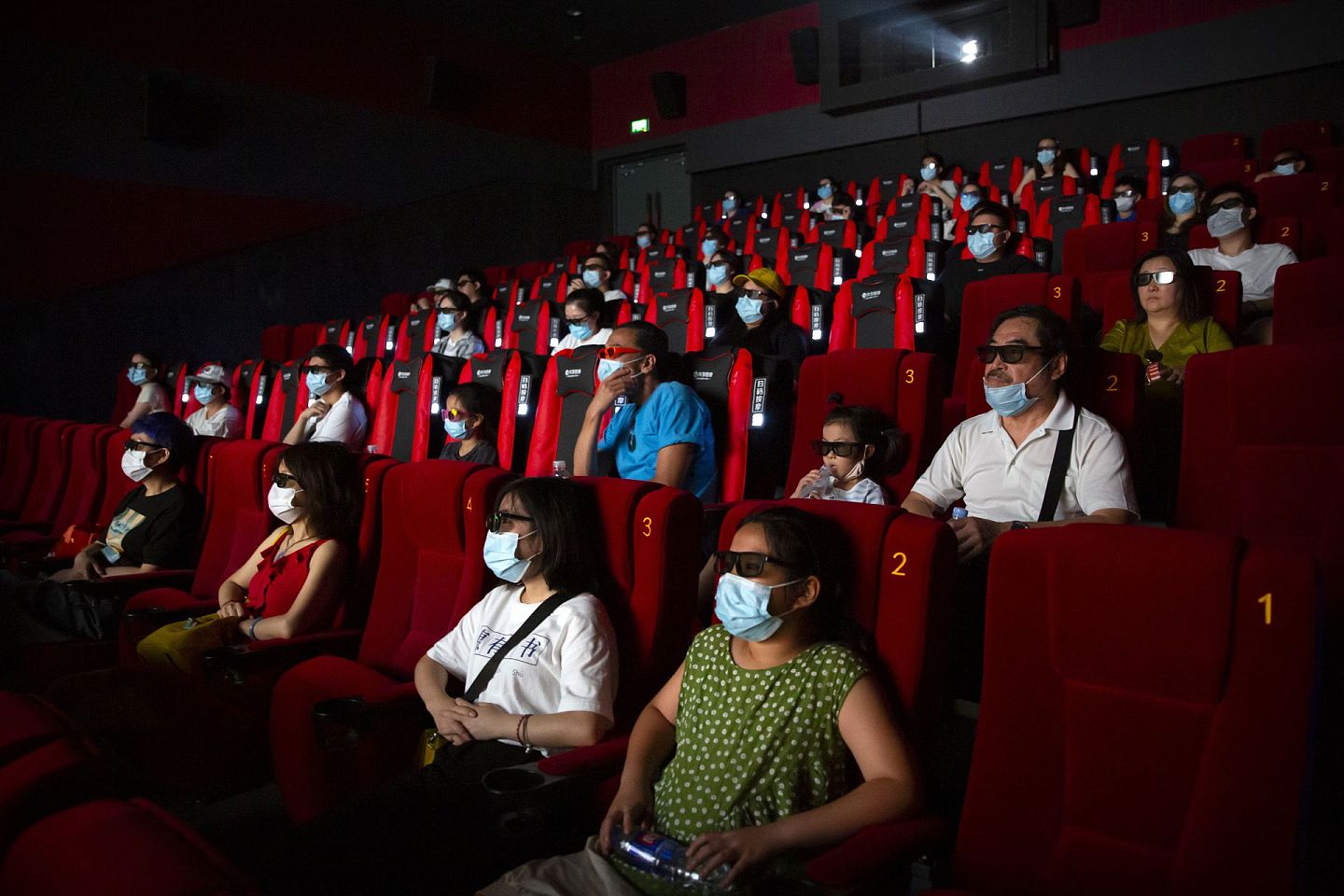 随着疫情逐渐减缓，中国各地电影院从7月20日起陆续复工。图为7月24日，北京一家电影院，人们戴着口罩观看电影《杜立德》。（AP）