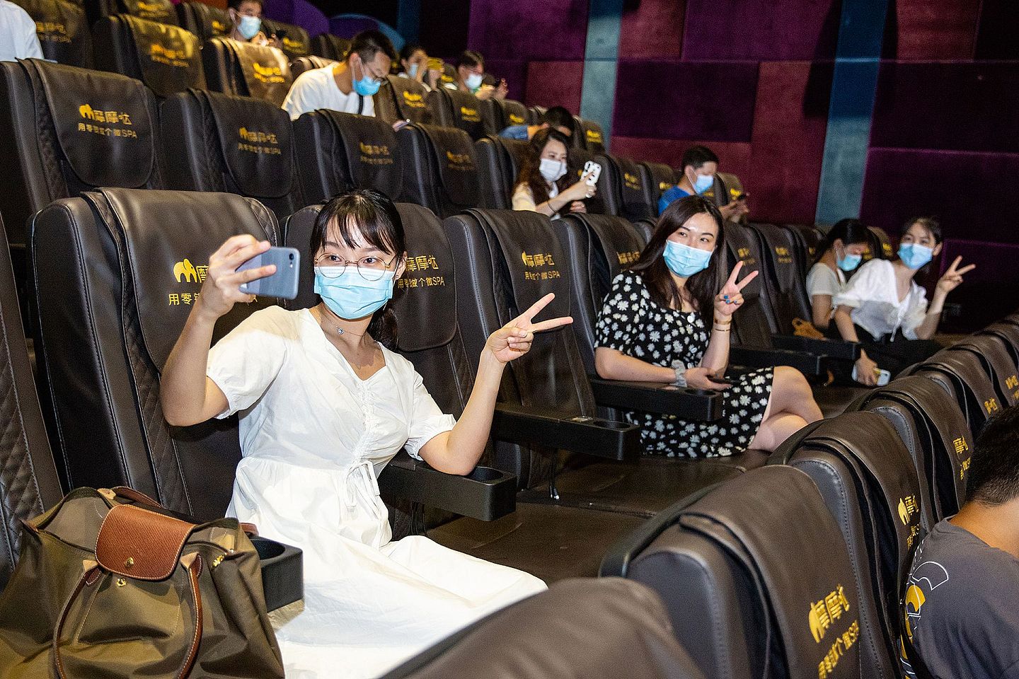 2020年7月19日晚，杭州，奥斯卡电影大世界复工后的首个零点场开映前，观众在影厅内戴着口罩分散就坐，并用手机自拍留念。（人民视觉）