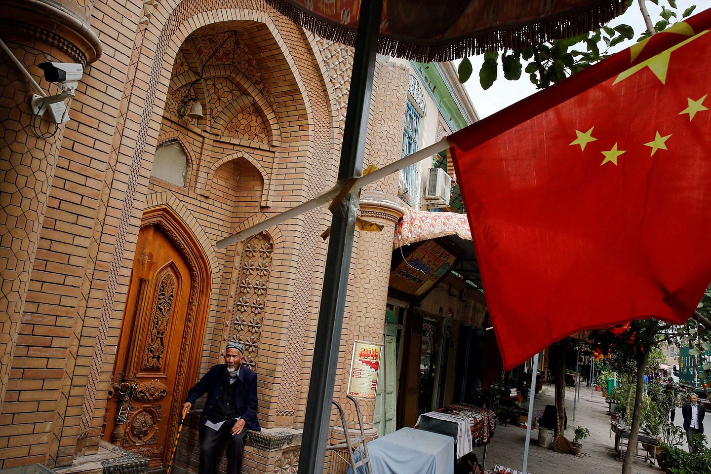 北京的诸多新疆政策引发外界争议。图为2018年9月6日，中国新疆喀什市一名老人站在中国国旗后面。（Reuters）