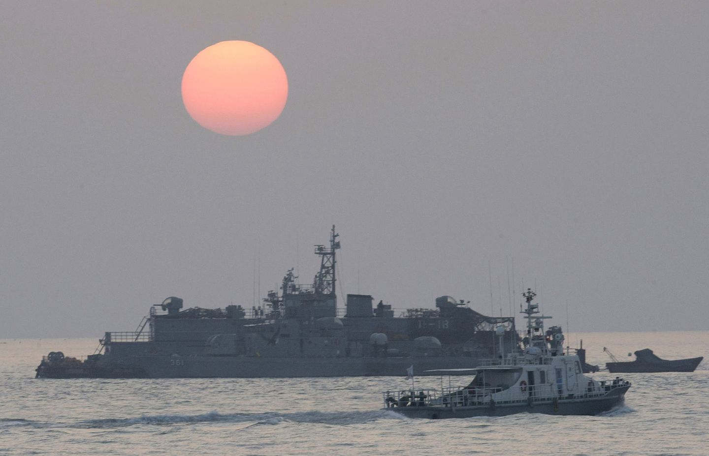图为2010年12月，一架韩国政府的船只驶近一艘韩国军舰。 （AP）