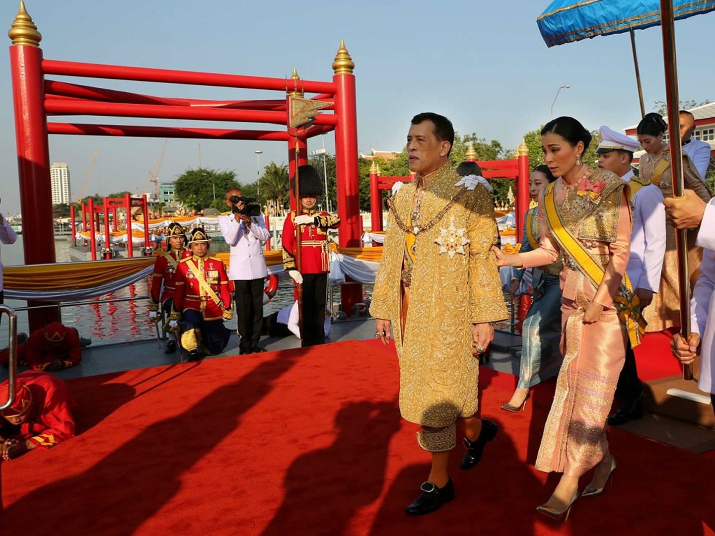 游行活动现场，泰国王后苏提达搀扶哇集拉隆功准备登上皇家游船。（Reuters）