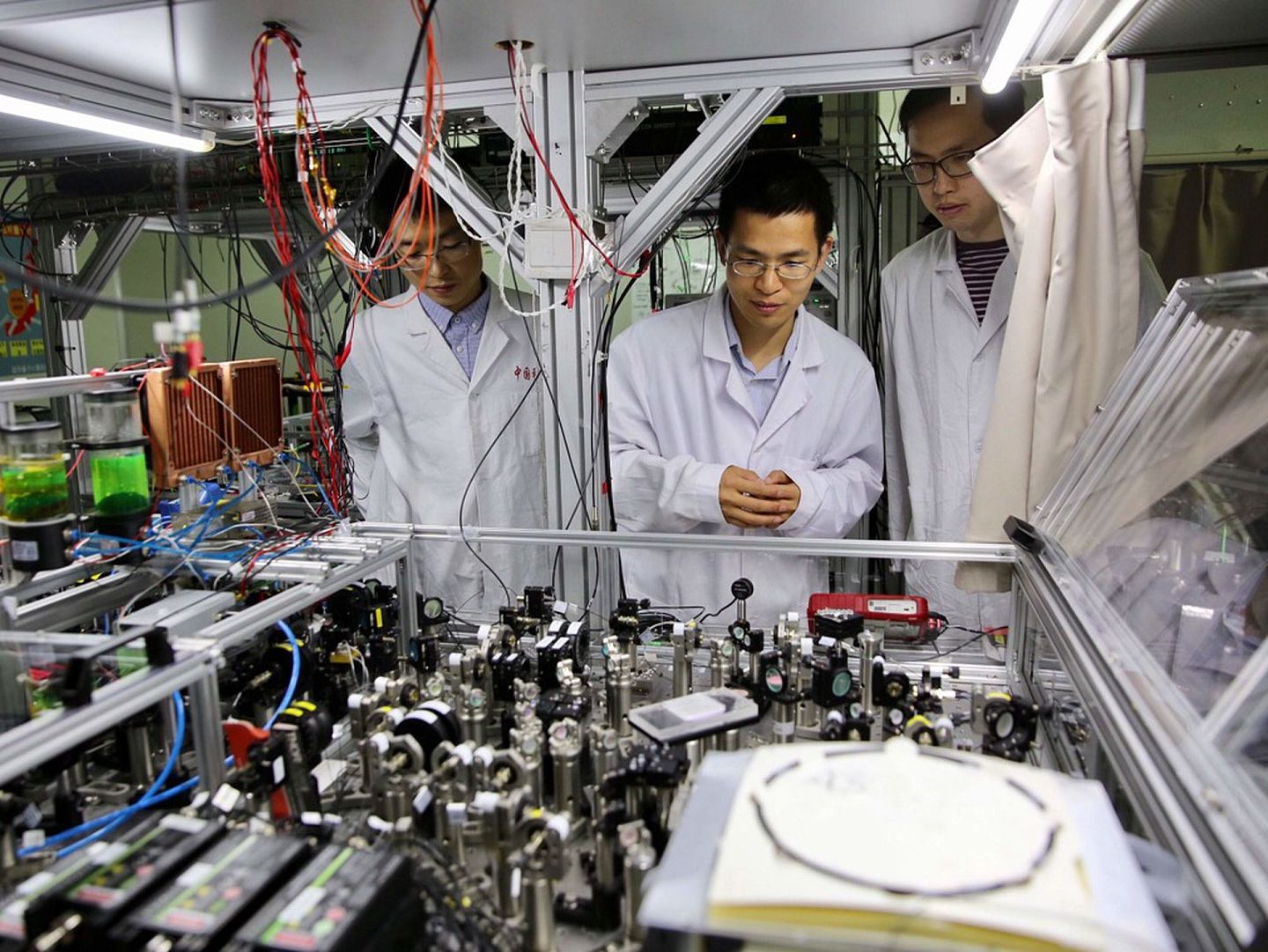 世界首台超越早期经典计算机的光量子计算机在中国诞生。 图为2017年5月3日，中国科学技术大学陆朝阳教授（中）和学生们在中科院量子信息和量子科技创新研究院上海实验室检查光量子计算机的运行情况。 （新华社）
