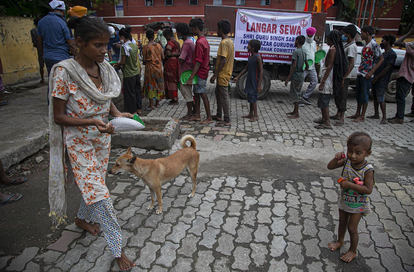 在阿萨姆邦的高哈蒂，当地的无家可归者在排队等候救济。他们中的很多人缺少口罩等基础防疫设备。（美联社）