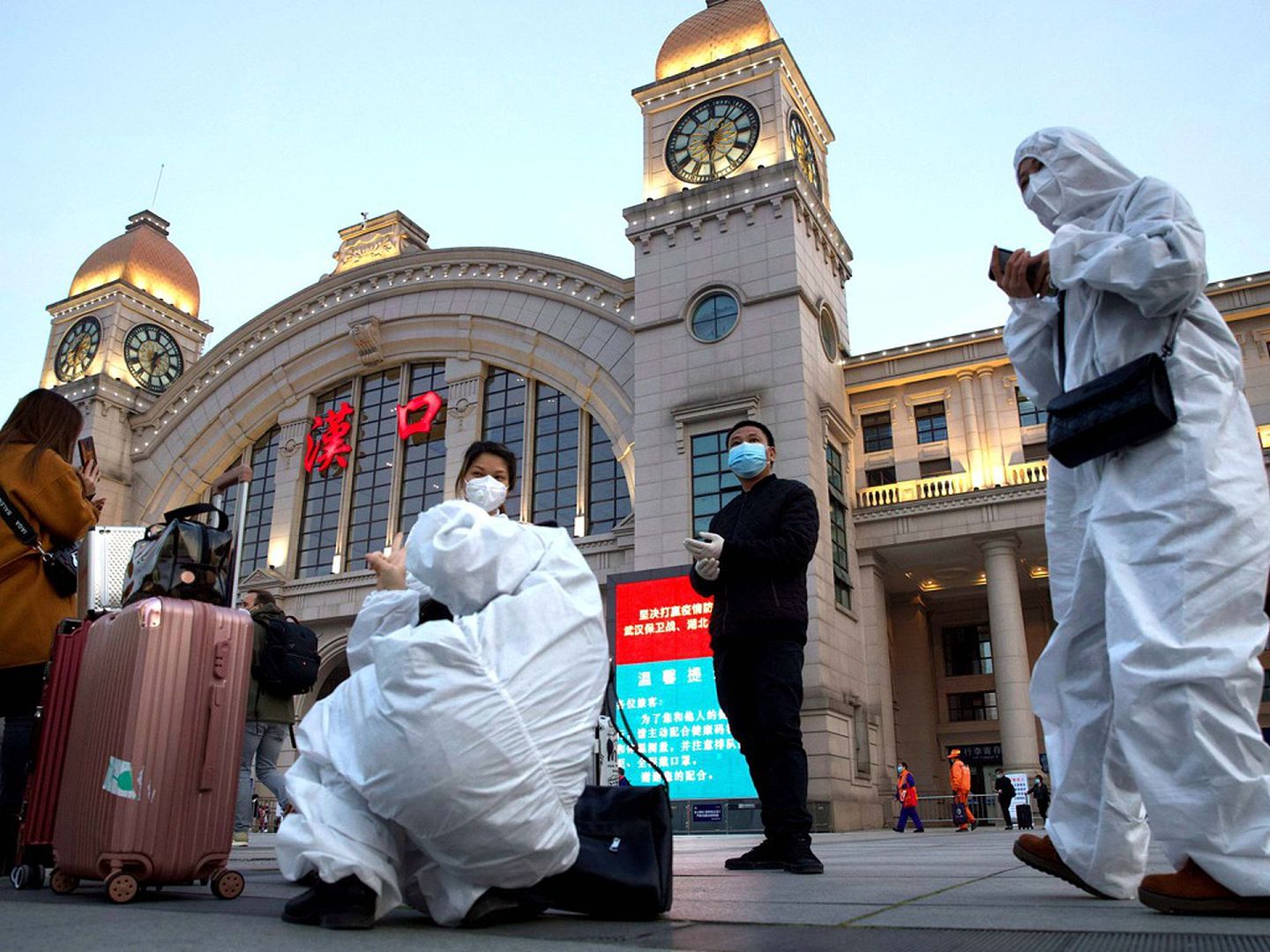 4月8日，在中国中部湖北省武汉市恢复列车运行之前，身穿防护服的乘客聚集在汉口火车站外。（AP）