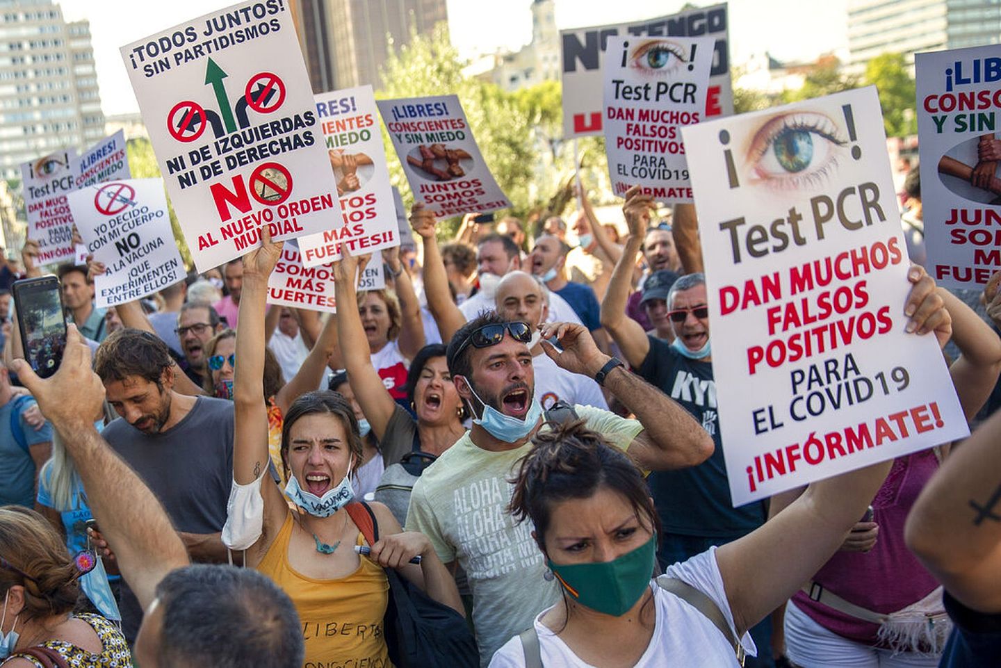 西班牙新冠肺炎疫情：图为8月16日西班牙马德里有民众上街，抗议防疫措施。有人举起标语牌，上面写有“PCR测试或会提供假阳性结果，请提示你自己。”（AP）