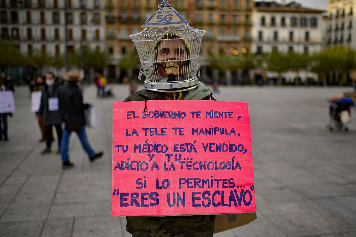 西班牙新冠肺炎疫情：图为10月17日一名男子在西班牙北部潘普洛纳城堡广场举起标语牌，对有关疫情的资讯表示反对。纸牌上写着的字样是：“政府撒谎、电视（内容涉）操纵、医生出卖你，而你深入科技之中。如你同意这个，你是一个奴隶。”（AP）