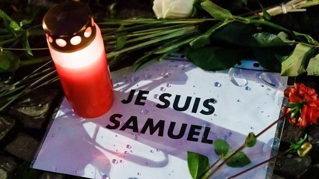 A candle and flowers are left next to a message in French that reads: 