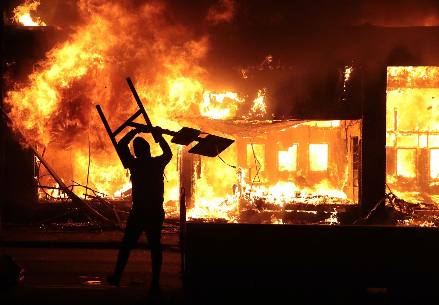 美国非裔男子弗洛伊德死亡激起示威。图为2020年5月29日，美国明尼苏达州明尼阿波利斯有示威者站于被焚毁的建筑物前。（资料图片／Getty Images）