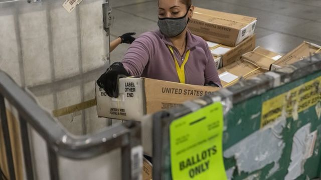 在俄勒冈州，一名邮政工作人员卸下数以千计装满选票的盒子。
