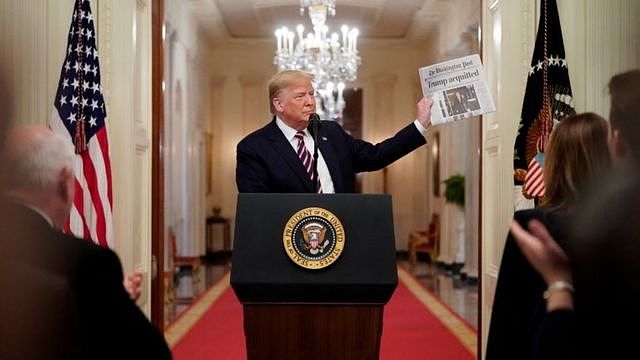 Donald Trump holds up a newspaper announcing his acquittal.