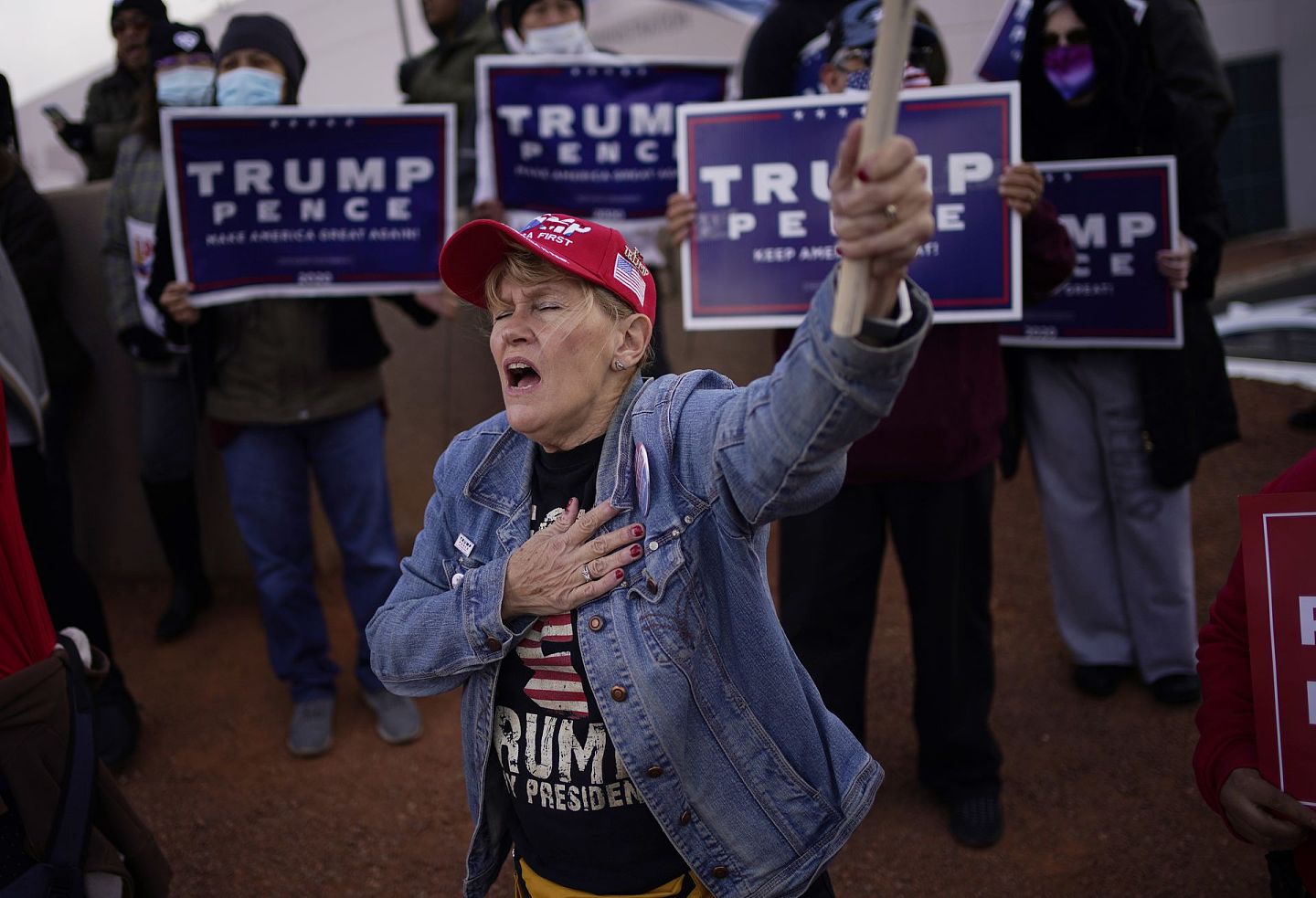 2020年的美国总统大选，进一步加剧了美国社会的撕裂和对立，图为2020年11月8日，北拉斯维加斯举行的克拉克县选举部外部选举抗议中，特朗普的支持者情绪激动地举起了手。（AP）