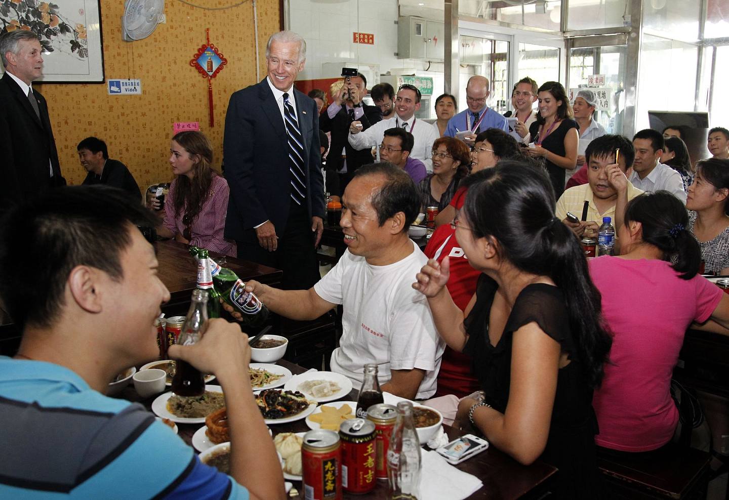 2011年8月18日，时任美国副总统的拜登和孙女娜奥米（Naomi Biden）来到姚记炒肝，与餐馆里的民众交流。 照片上，正在就餐的普通中国民众有的诧异，有的淡定，还有的直接掏出手机拍照留念，还有的要求与拜登合影。 （Getty）