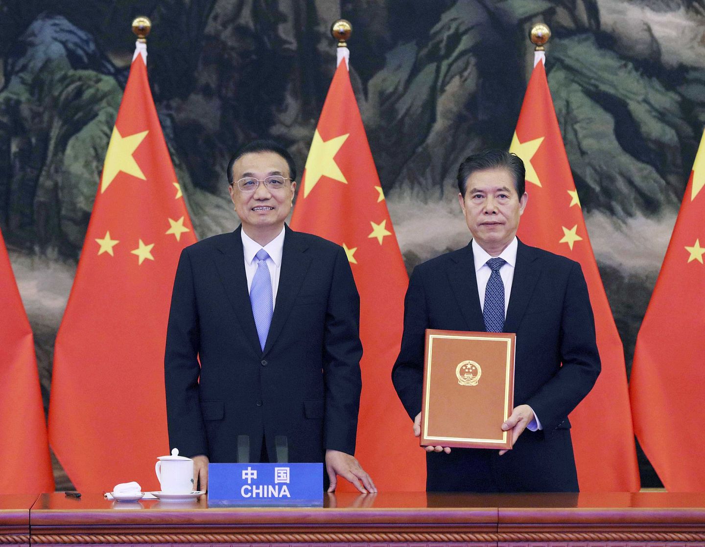 2020年11月15日， 中国国务院总理李克强（左）在北京人民大会堂出席RCEP签字仪式，中国商务部部长钟山代表中国在RCEP协定上签字。（新华社）