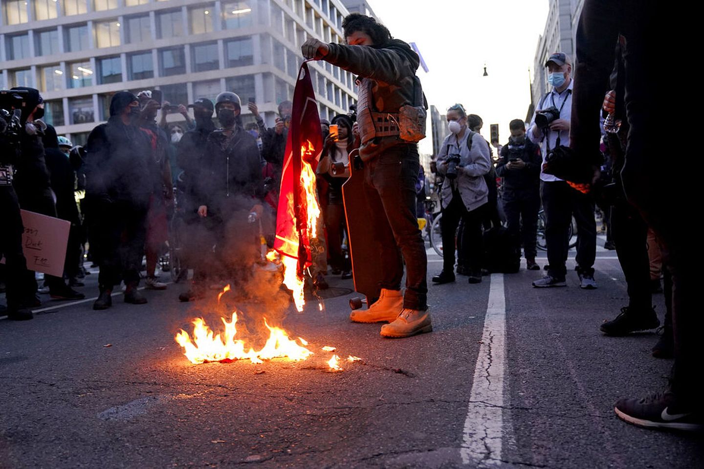 2020年11月14日，特朗普的支持者在华盛顿游行过后，一名与他们立场相反的示威人士焚烧特朗普的竞选宣传旗帜。（AP）