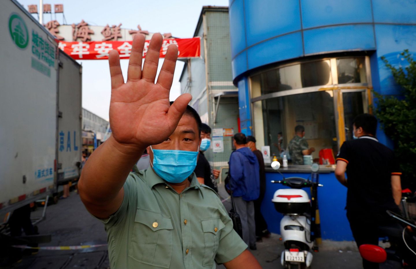 一名戴着口罩的保安试图制止拍摄，该市场因新冠病毒感染被发现而关闭。（路透社）