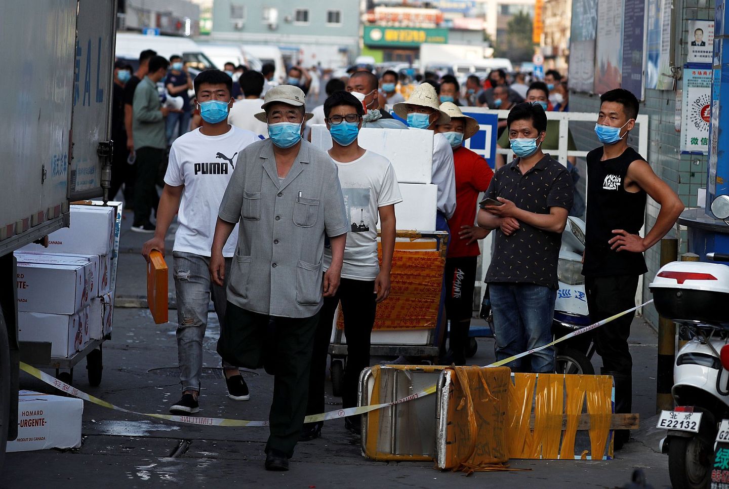 北京京申海鲜市场发现新冠病毒后关闭，人们戴着口罩等待检测。（路透社）