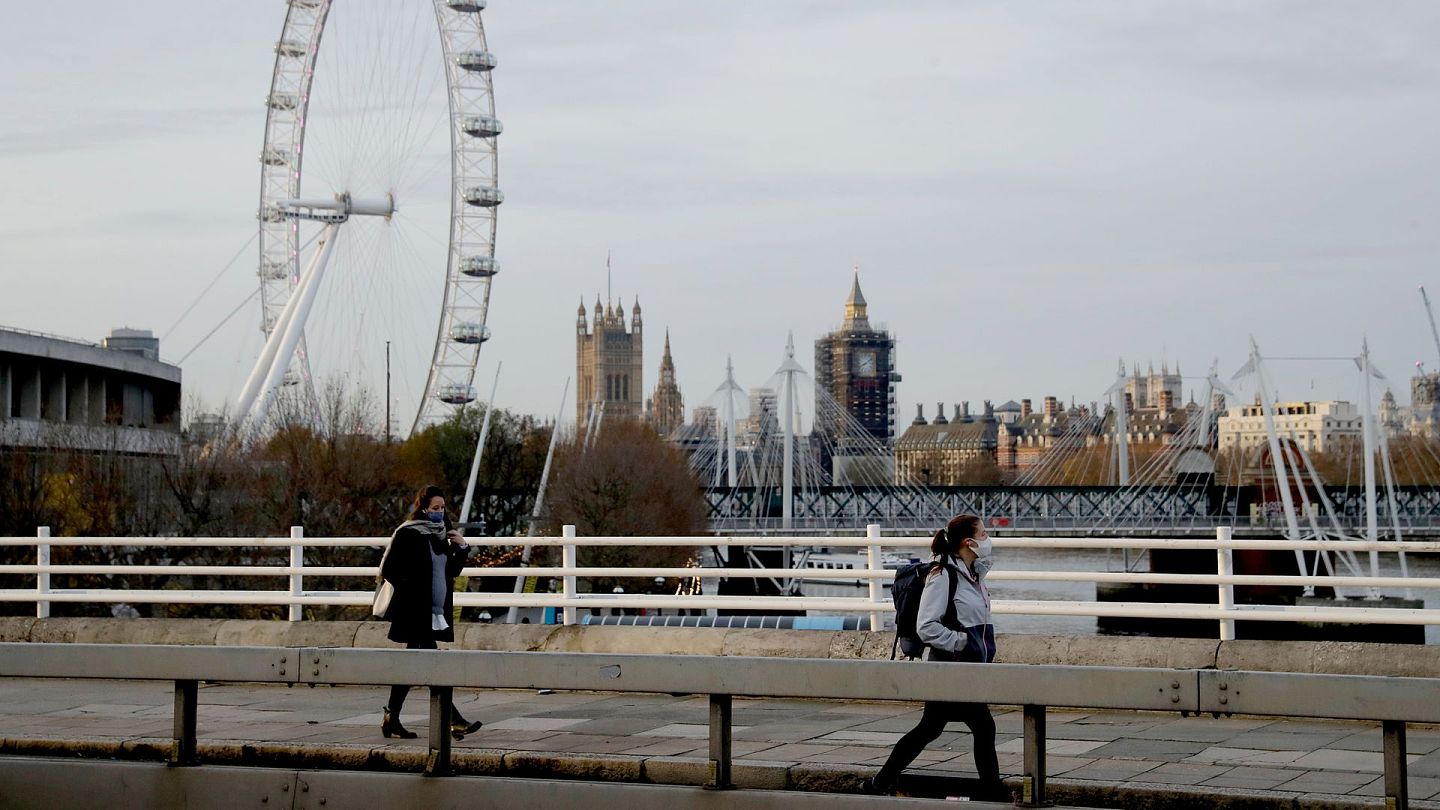 图为11月20日走在英国伦敦一条桥上的行人，她们的后方是英国国会所在地。（AP）