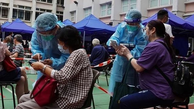Medical workers in protective suits attend to people at a makeshift community testing centre for the coronavirus disease (COVID-19), in Hong Kong