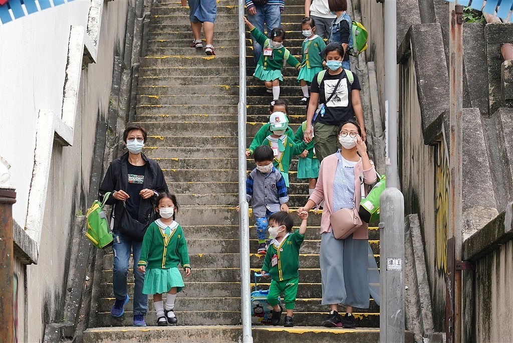 香港第四波疫情29日再创新高，香港教育局下午宣布中小学、幼儿园自12月2日起全面停课。 图为香港一间小学家长接送孩子上下学。 （中新社）