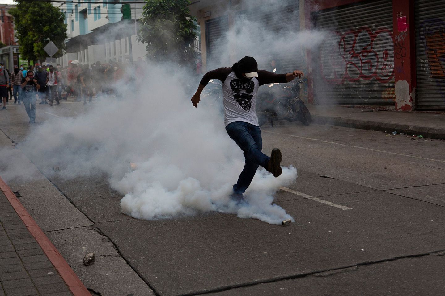 危地马拉示威者将催泪弹踢回警察方向。（AP）