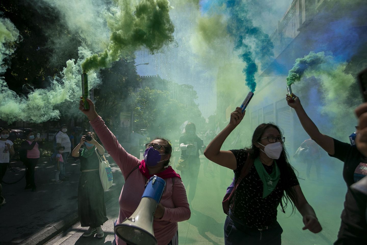 危地马拉市，示威女子沿途燃起绿色烟雾。（AP）