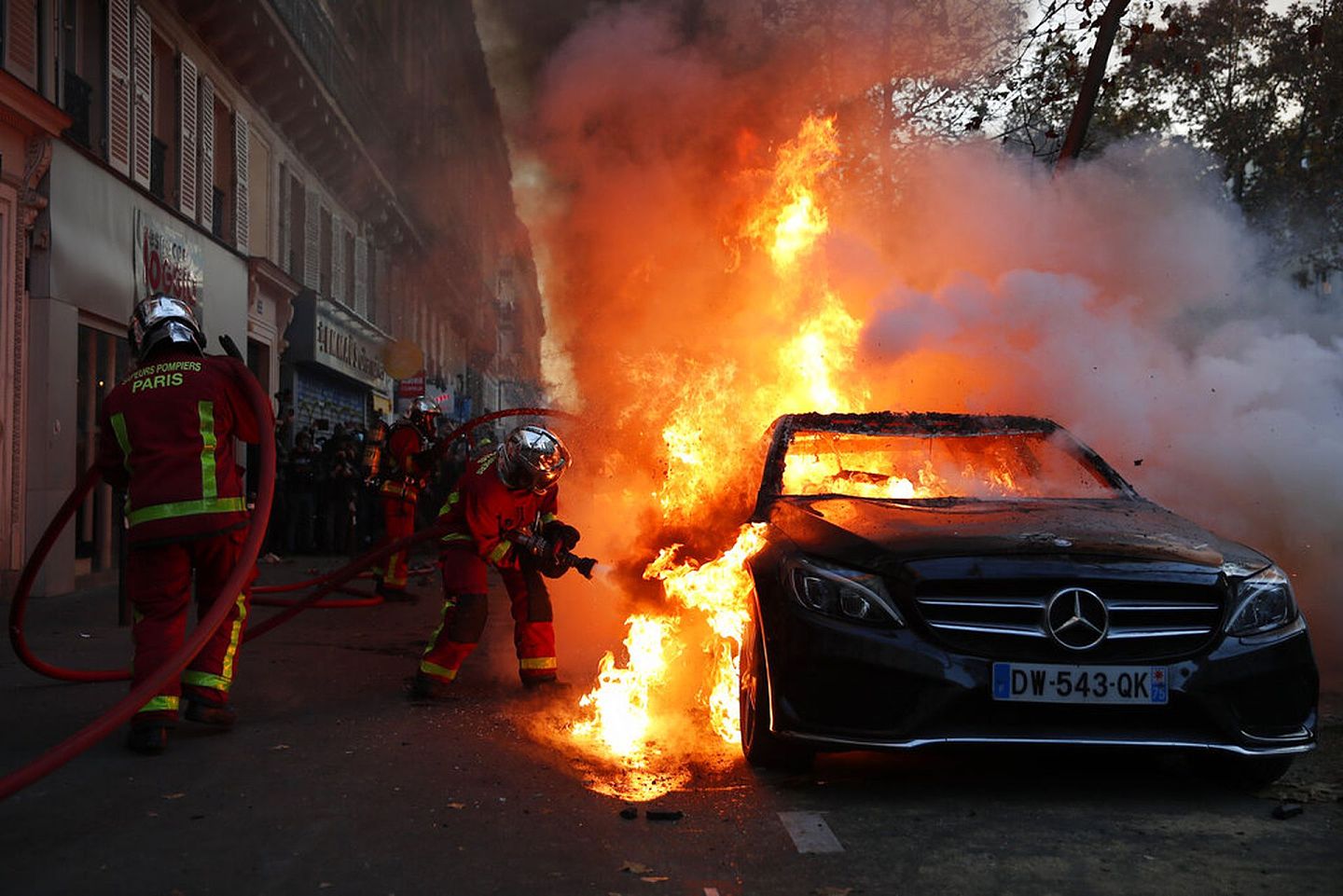 法国反安全法示威：图为11月28日巴黎消防人员救熄一架在示威进行期间起火的汽车。（AP）