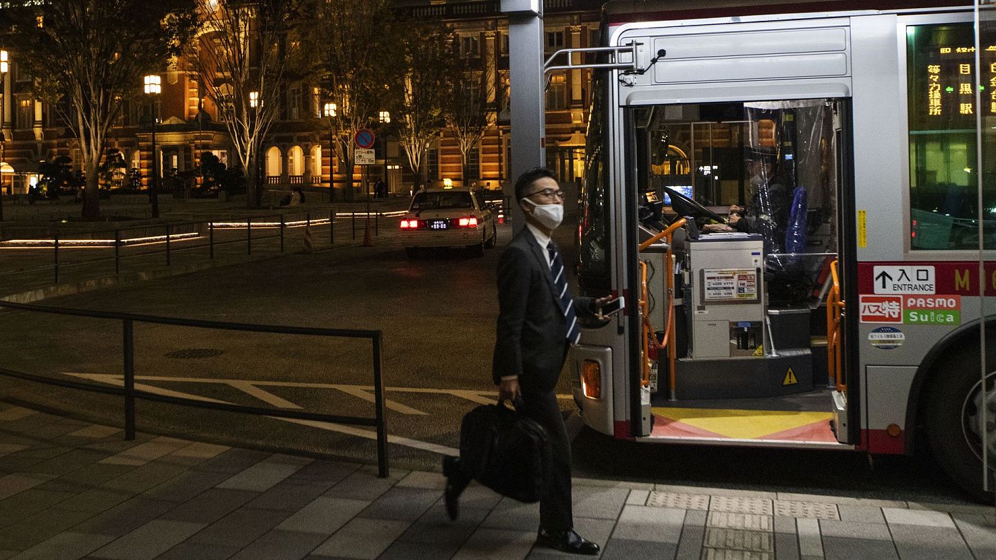 进入冬季以来，日本疫情加剧。图为2020年11月12日，一名佩戴口罩的行人在东京站附近准备登上公交车。（AP）