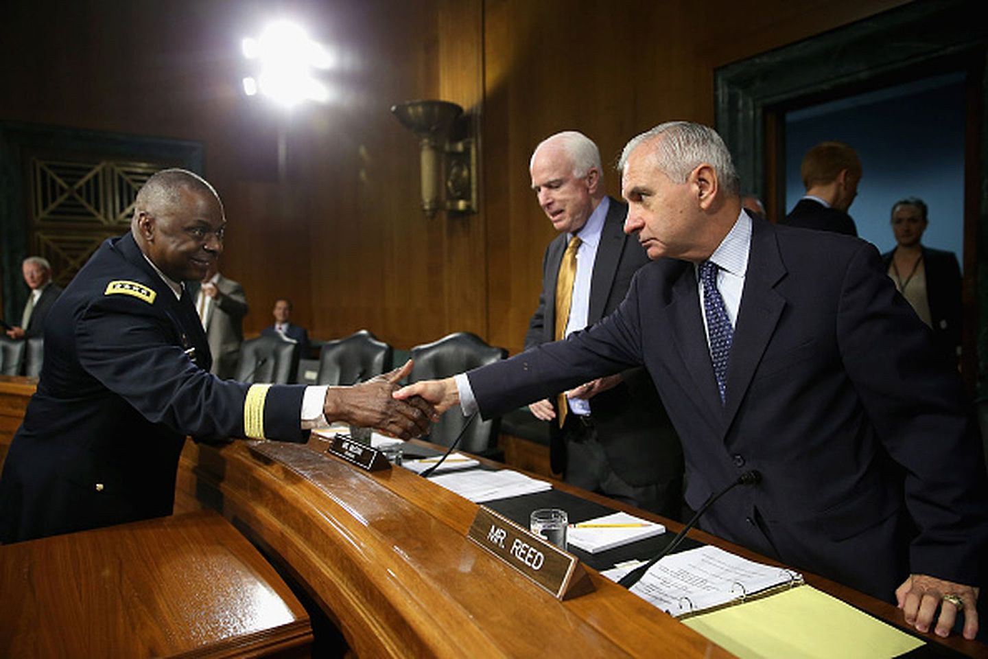 2015年9月16日，美国中央司令部司令奥斯汀（左）在华盛顿特区国会山的参议院办公大楼举行听证会开始之前，向参议院军事委员会成员里德（Jack Reed）（右）和主席麦凯恩（John McCain）（左）问候。听证会就美国当时正在进行的打击伊拉克和黎凡特伊斯兰国(ISIL)的军事行动举行。（Getty）