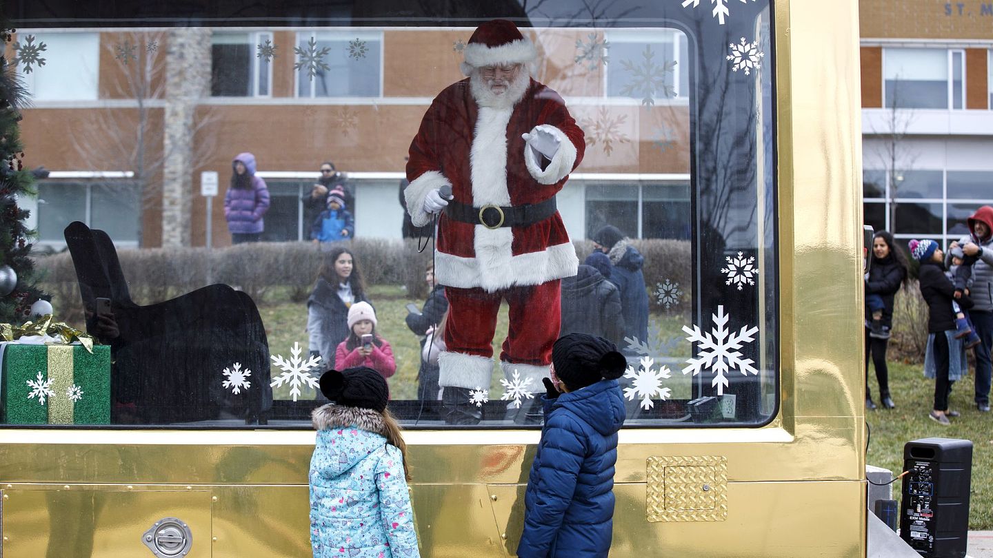 新冠肺炎：图为12月13日，加拿大安大略省一名男子打扮成圣诞老人，隔着玻璃与小朋友见面。（AP）