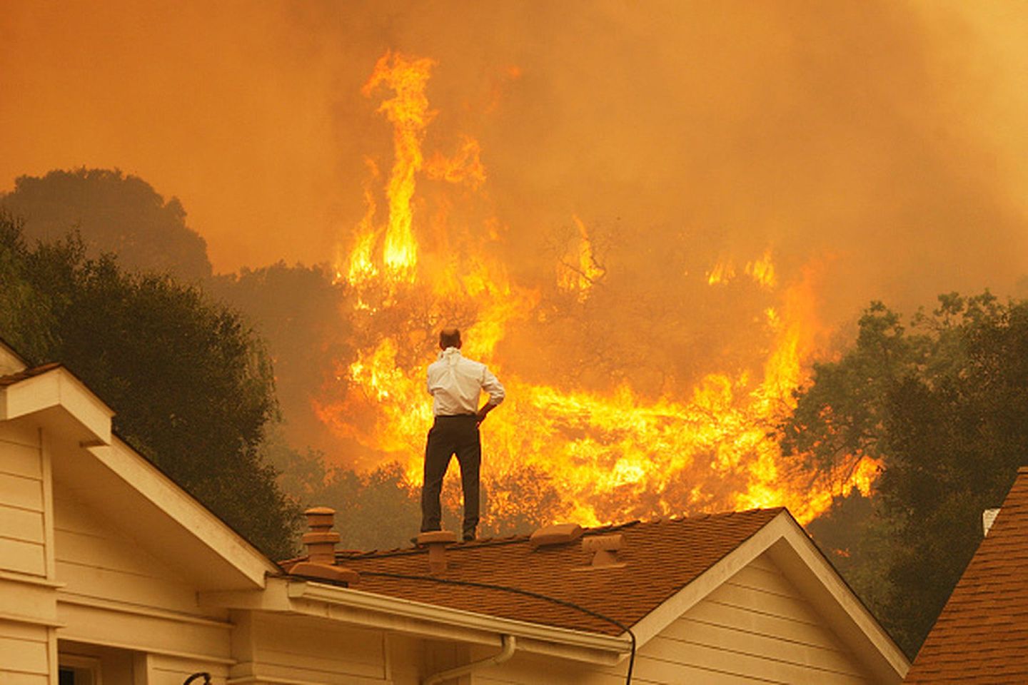 2013年5月3日，加利福尼亚州卡马里洛附近的斯普林斯之火继续燃烧，一个男人站在屋顶上看着大火蔓延。（Getty）