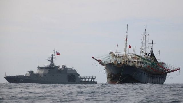 One vessel, part of a fleet of hundreds of Chinese fishing boats, sails next to a Chilean Navy ship in Pacific Ocean international waters near Chile