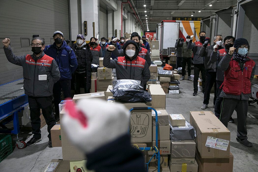 快递员们在首尔一家物流仓库中举起拳头，唱了一首工会歌曲。大多数快递员无法受益于保护企业全职员工的劳动法。