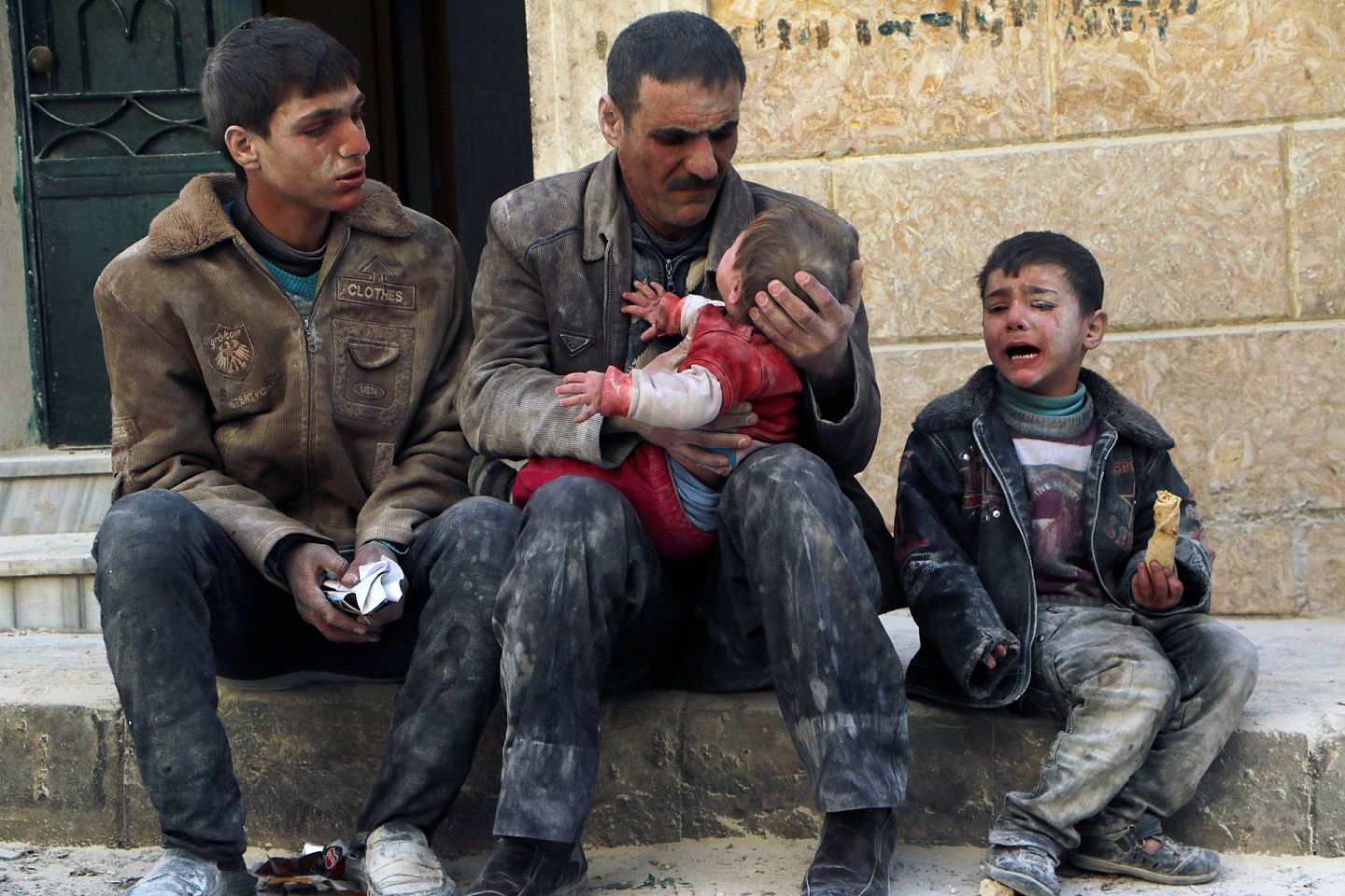 2014年2月14日，在阿勒颇发生的一场空袭后，一名男子抱着一名从废墟中救出的婴儿。（Reuters）