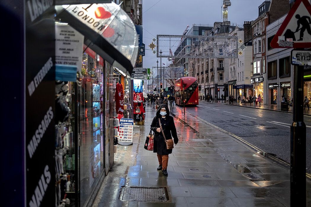 伦敦实施三级防控管制的第一天，一名女子走在雨中的牛津街。该市已采取了更严格的限制措施。