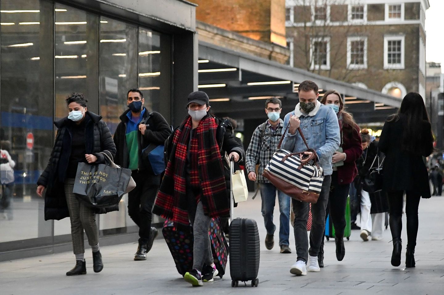 2020年12月20日，英国政府对疫情实施了更严格的分级限制。图为游客在伦敦国王十字车站外行走。（Reuters）