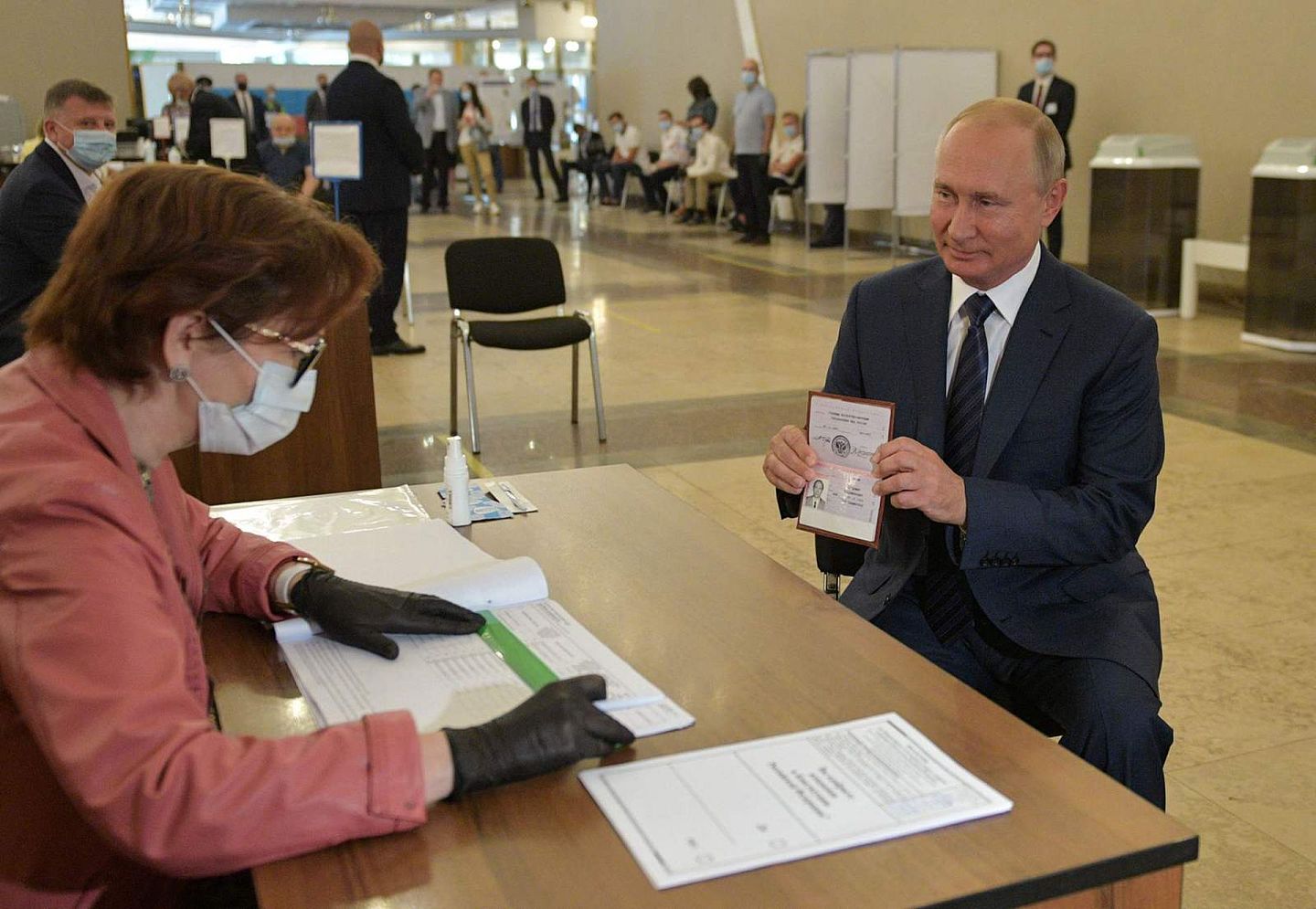 普京在投票现场出示自己的证件，并最终投下一票。普京全程没有戴口罩。（Reuters）