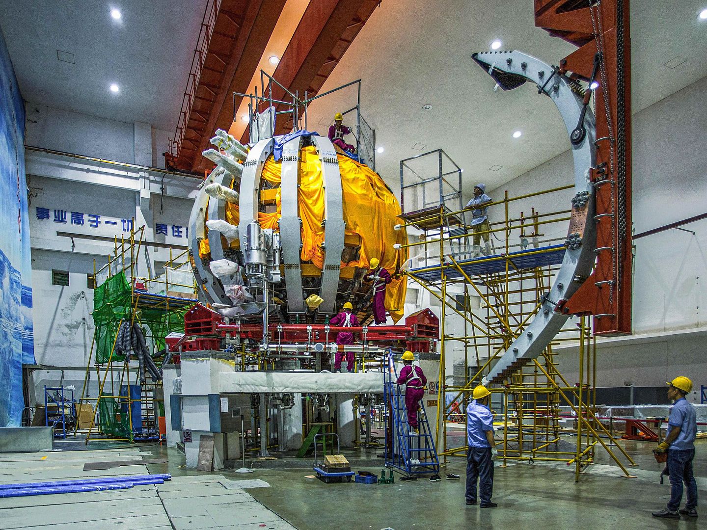 2020年12月4日，中国环流器二号M在位于成都的核工业西南物理研究院建成。图为西南物理研究院工作人员在安装调试中国环流器二号M装置时进行环向场线圈外弧段吊装工作。（新华社）