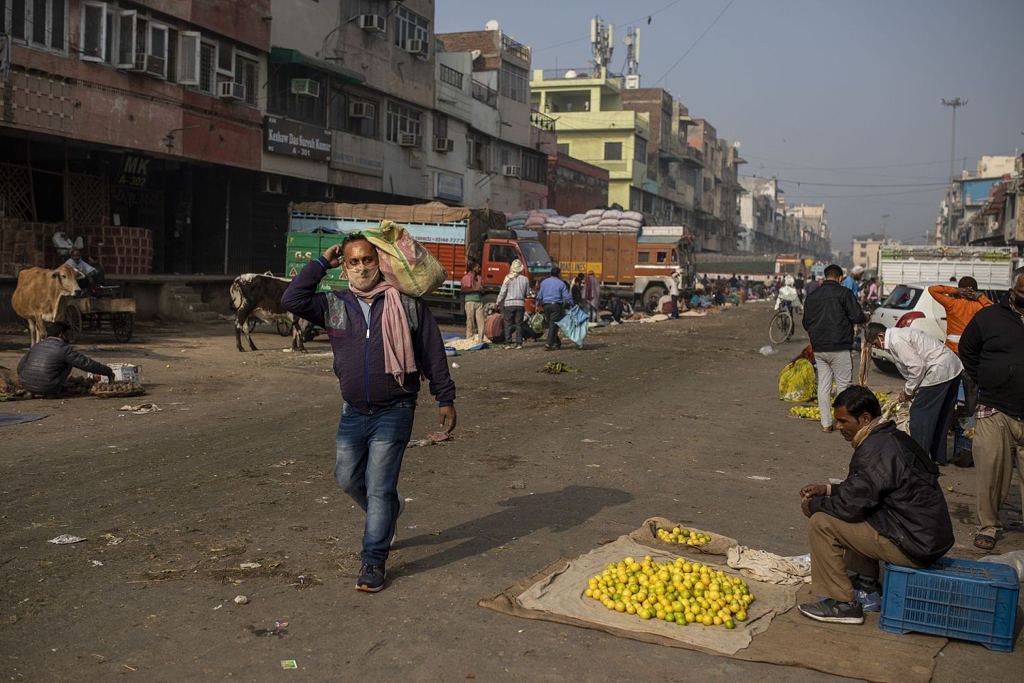 2020年12月8日，星期二，在印度新德里几乎无人光顾的批发市场，一名男子从路边卖柠檬的小贩身边走过。（AP）