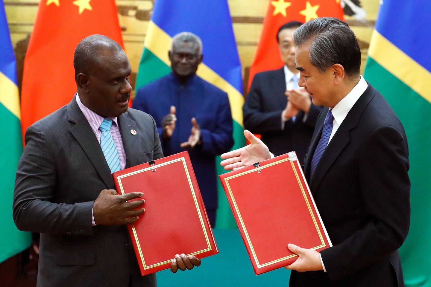 2019年10月9日星期三，所罗门群岛总理玛拿西·索加瓦雷(中左)和中国总理李克强(中右)在北京人民大会堂观看所罗门群岛外交部长耶利米·马奈莱(左)和中国外交部长王毅签署文件。（AP）