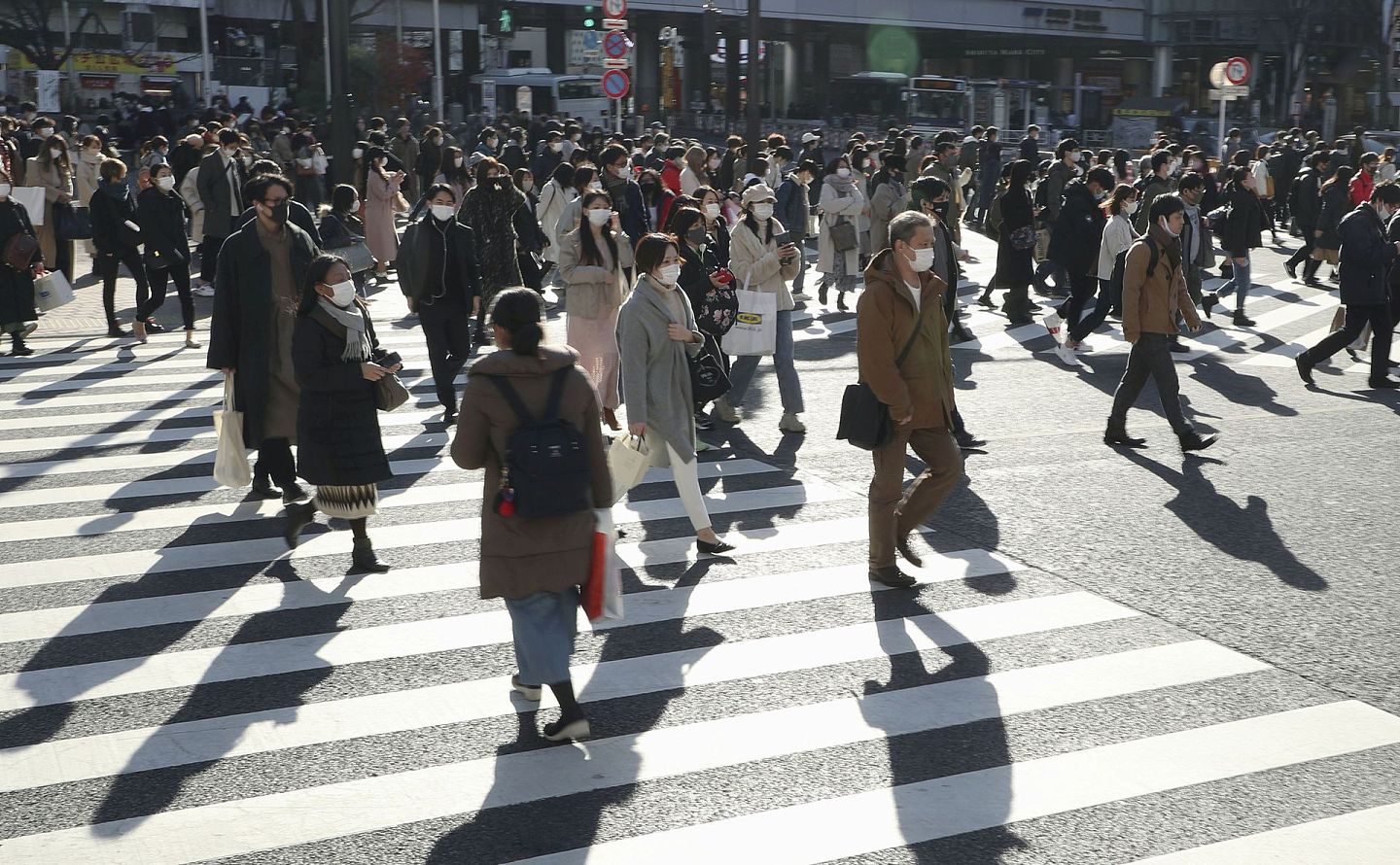 图为12月26日，日本池袋街上行人在过马路。该国新冠疫情仍然持续，行人均戴着口罩出外。（Reuters）