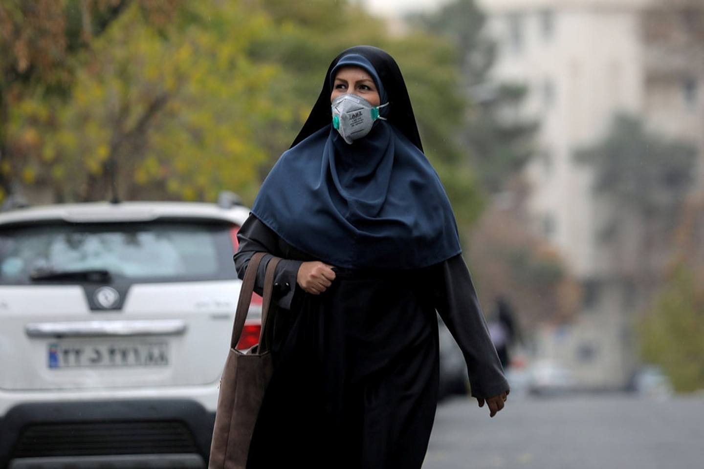 图为12月16日，伊朗德克兰一名戴着口罩的女子正走在街上。 （Reuters）