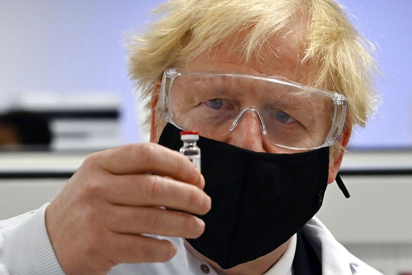 英国首相约翰逊检视手上一瓶牛津及阿斯利康研发的疫苗。（美联社）