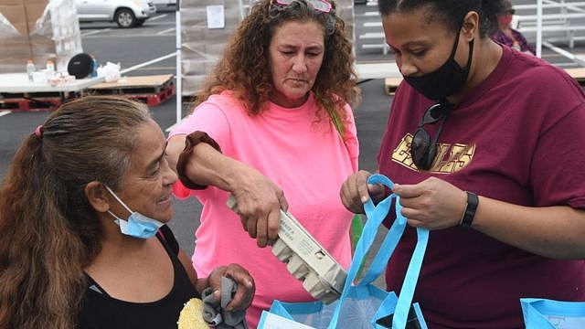A volunteer hands out assistance for laid off Walt Disney World cast members and others at a food distribution event on December 12, 2020 in Orlando, Florida