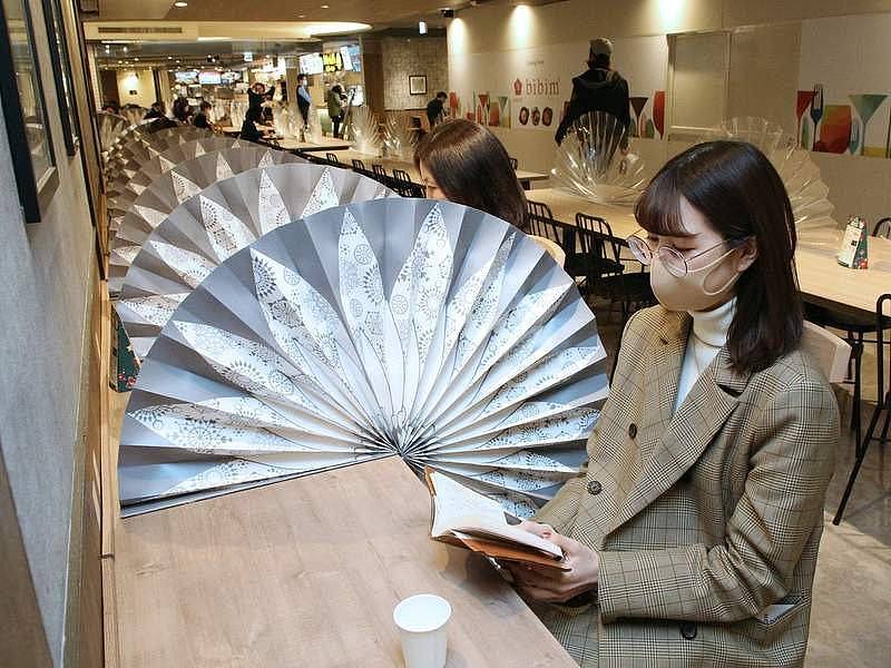 网友贴出日本餐厅的防疫措疫，用纸扇的材质当隔离板被批华而不实。 图／PTT