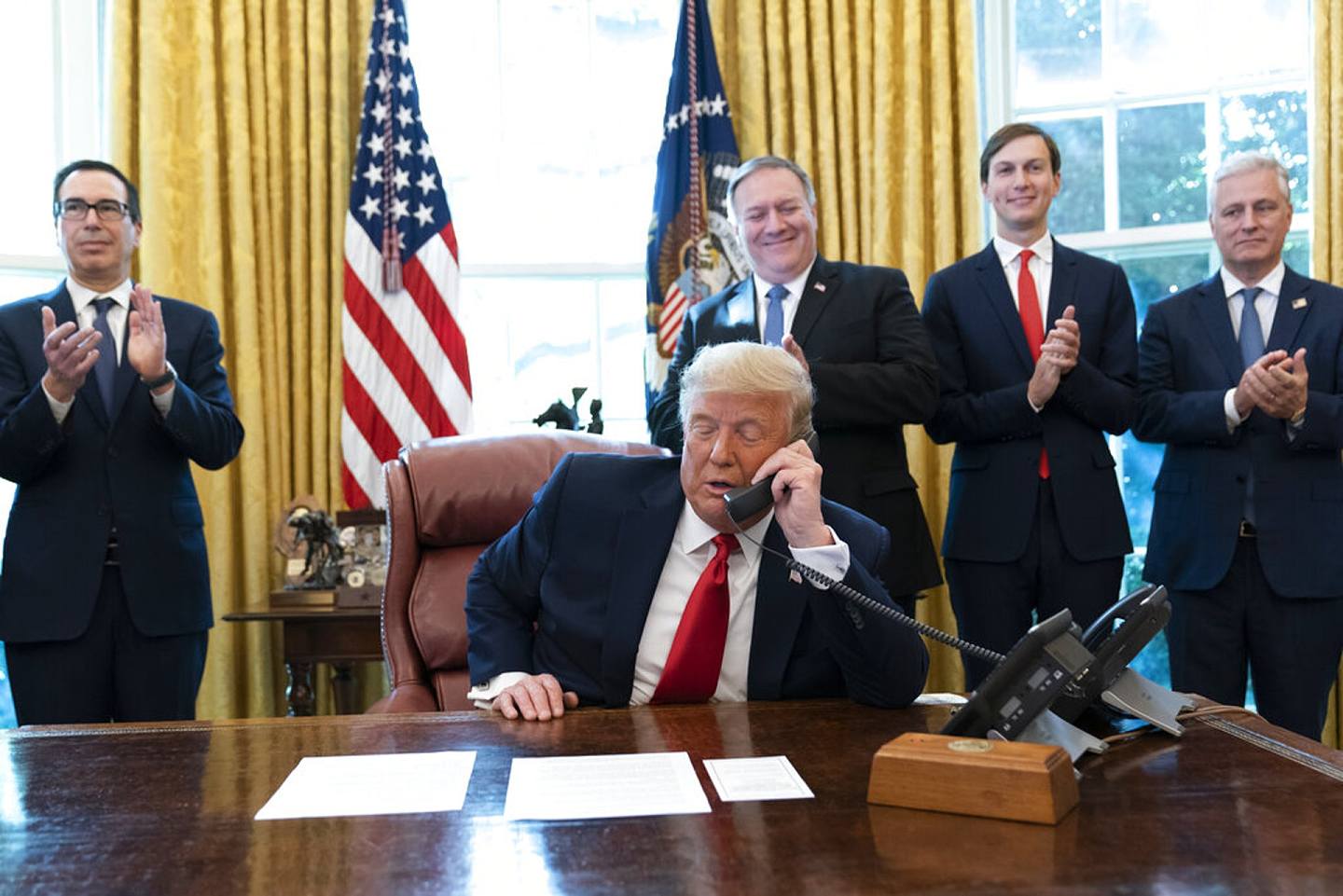 圖為美國總統特朗普10月23日在白宮橢圓形辦公室內與蘇丹及以色列領導人通電話。站在他後方的是財長姆努欽（左起）及國務卿蓬佩奧等人。（AP）