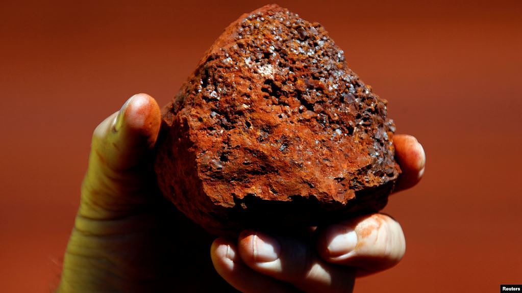 资料照：一名澳大利亚矿工手握澳西部地区产出的一块铁矿石。