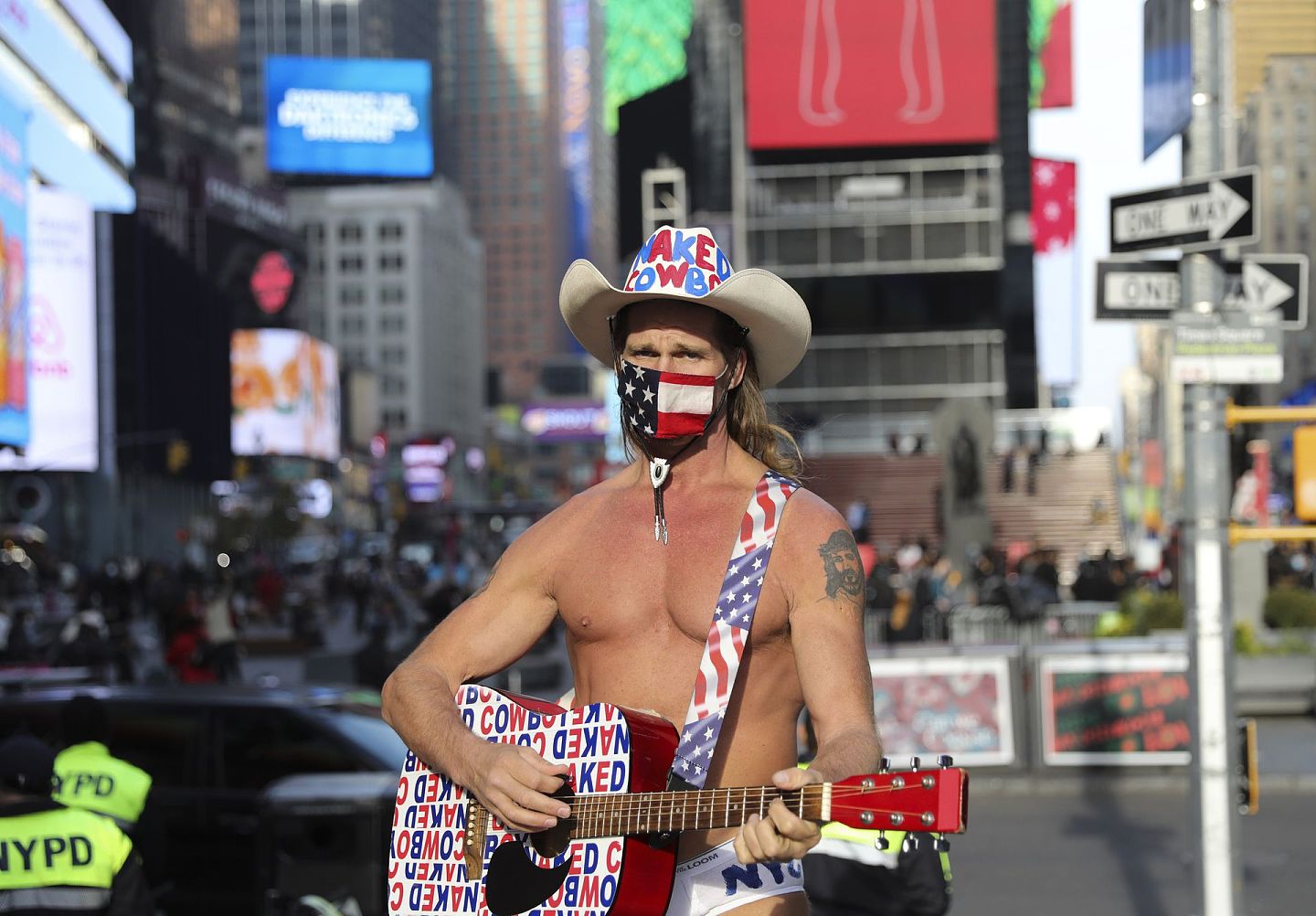 2020年12月11日，美国街头表演者“裸体牛仔”罗伯特·伯克戴着口罩在美国纽约的时报广场进行表演。（ 新华社）