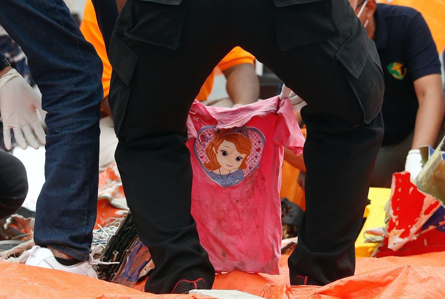 1月10日，搜救人员在印尼首都雅加达国际集装箱码头手持一件粉红色T恤。（Reuters）