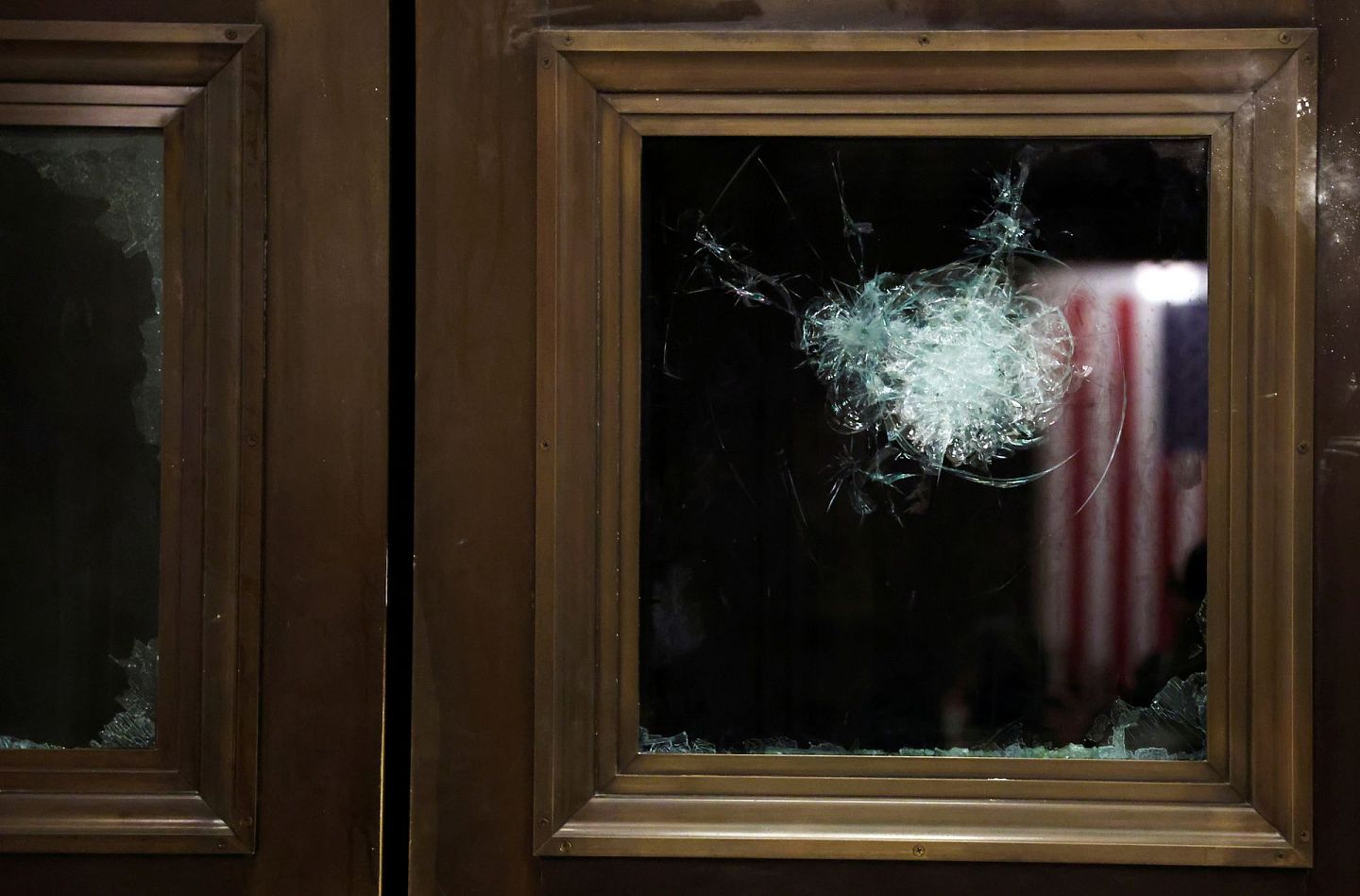 国会山庄一块被打裂的玻璃映照出一支美国国旗。（路透社）