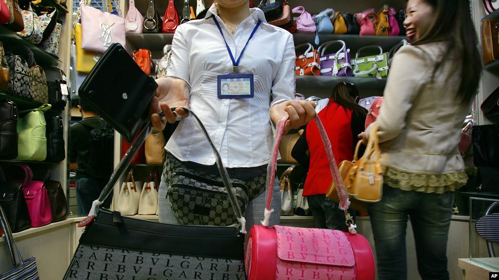 在北京丝绸市场中，一名售货员在展示品牌手提包。检查人员此前在对市场上假冒或盗版商品的突击检查中没收了300多件物品。（资料照片）